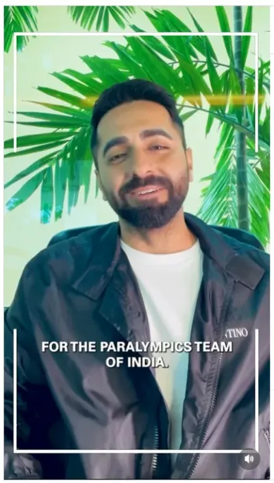 Ayushmann Khurrana in a black jacket and white t-shirt smiling warmly, with the subtitle "For the Paralympics Team of India" against a tropical plant backdrop.