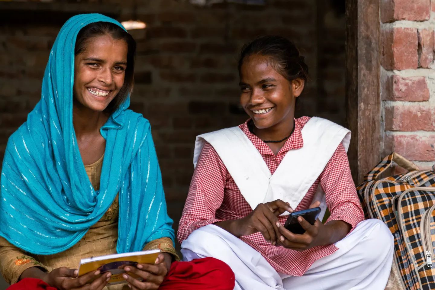 Two young women smiling and laughing lookin at the camera