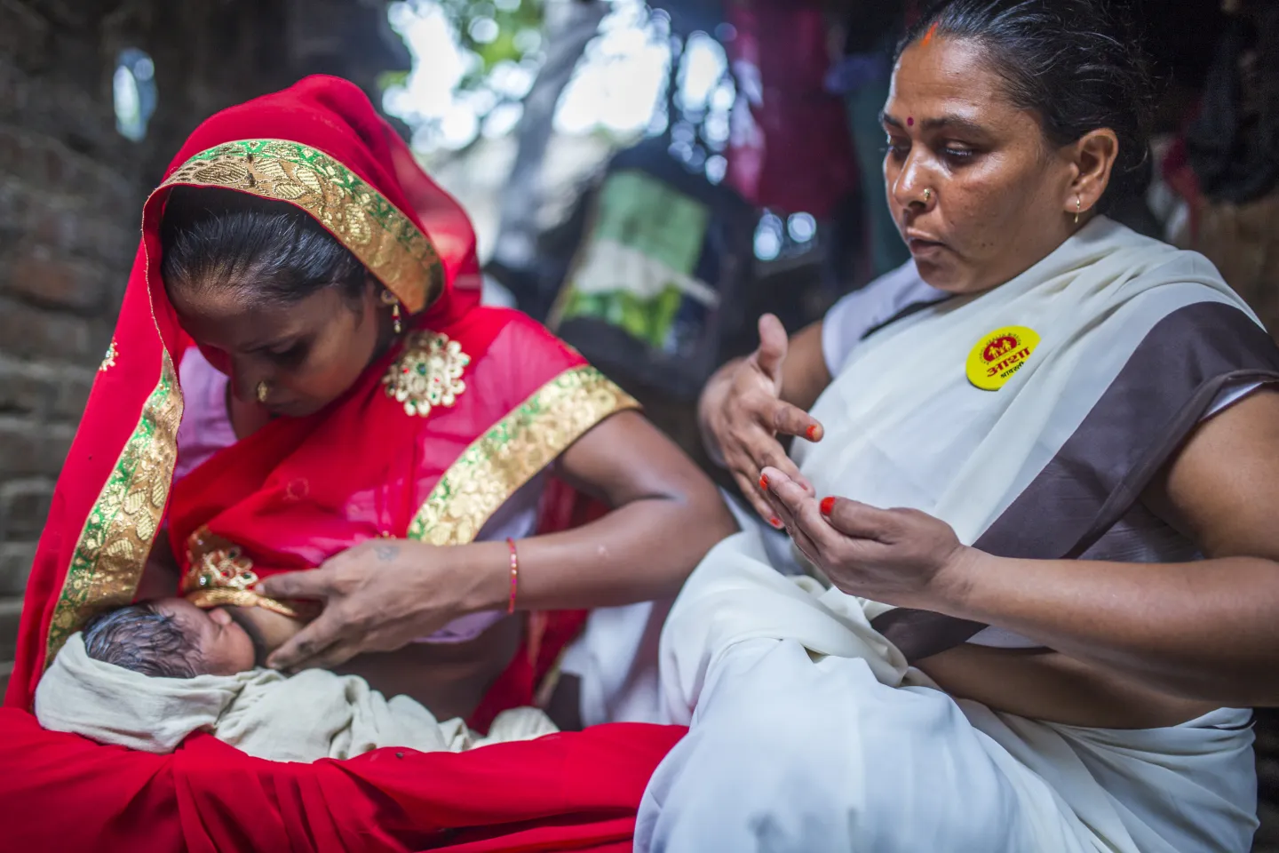 Seeta Devi feeds her newborn child as Kiran Devi, an Accredited Social Health Activist (ASHA) demonstrates her correct feeding technique inside her home in the Shrawasti district of the northern Indian state of Uttar Pradesh.