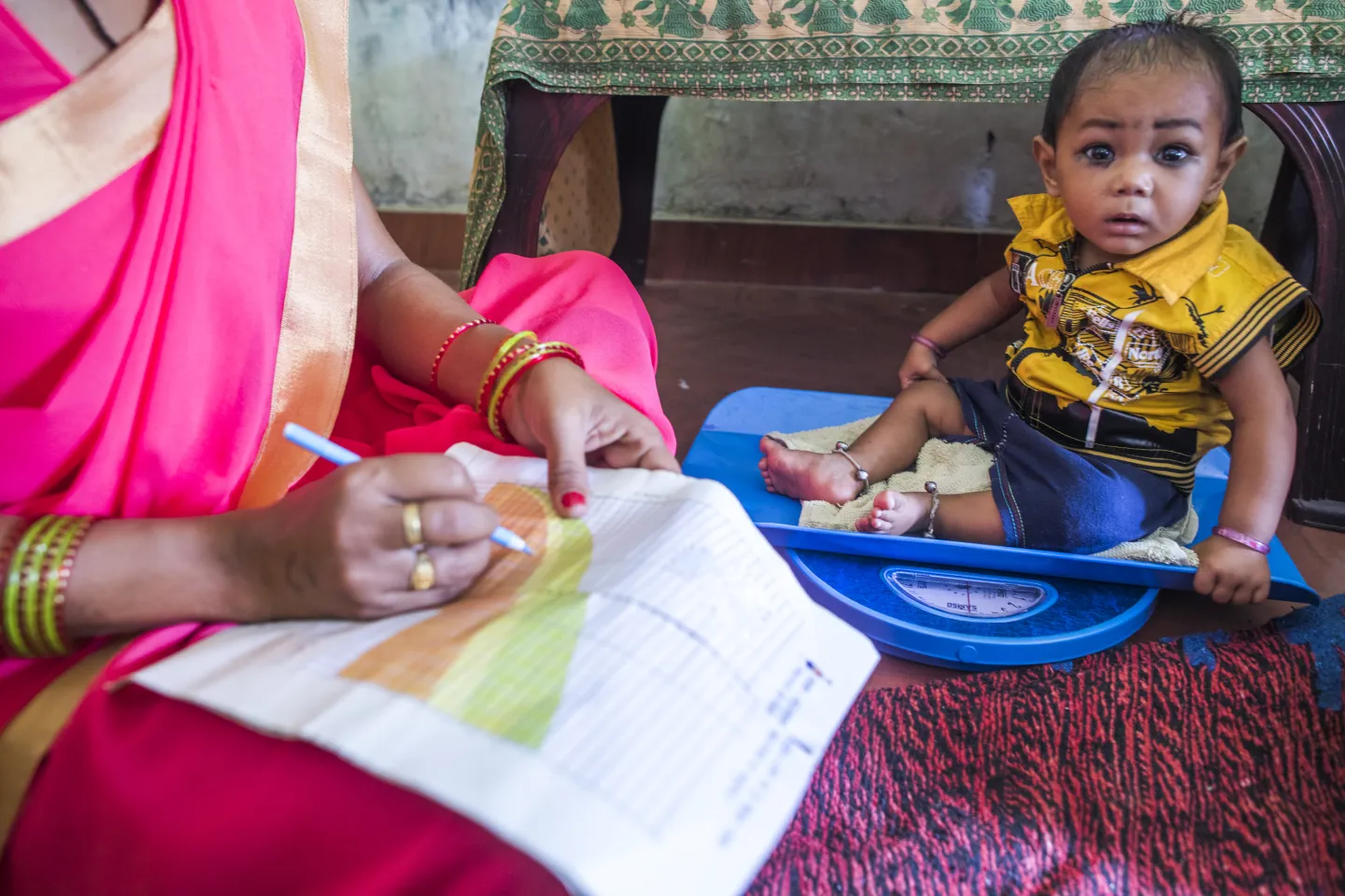 An Aanganwadi worker weighs a child on a digital scale as she records the details on a MCP card a during a meeting as part of Village Health and Nutrition Day (VHND) in Motipur Kala Aanganwadi Centre in Shrawasti, Uttar Pradesh.