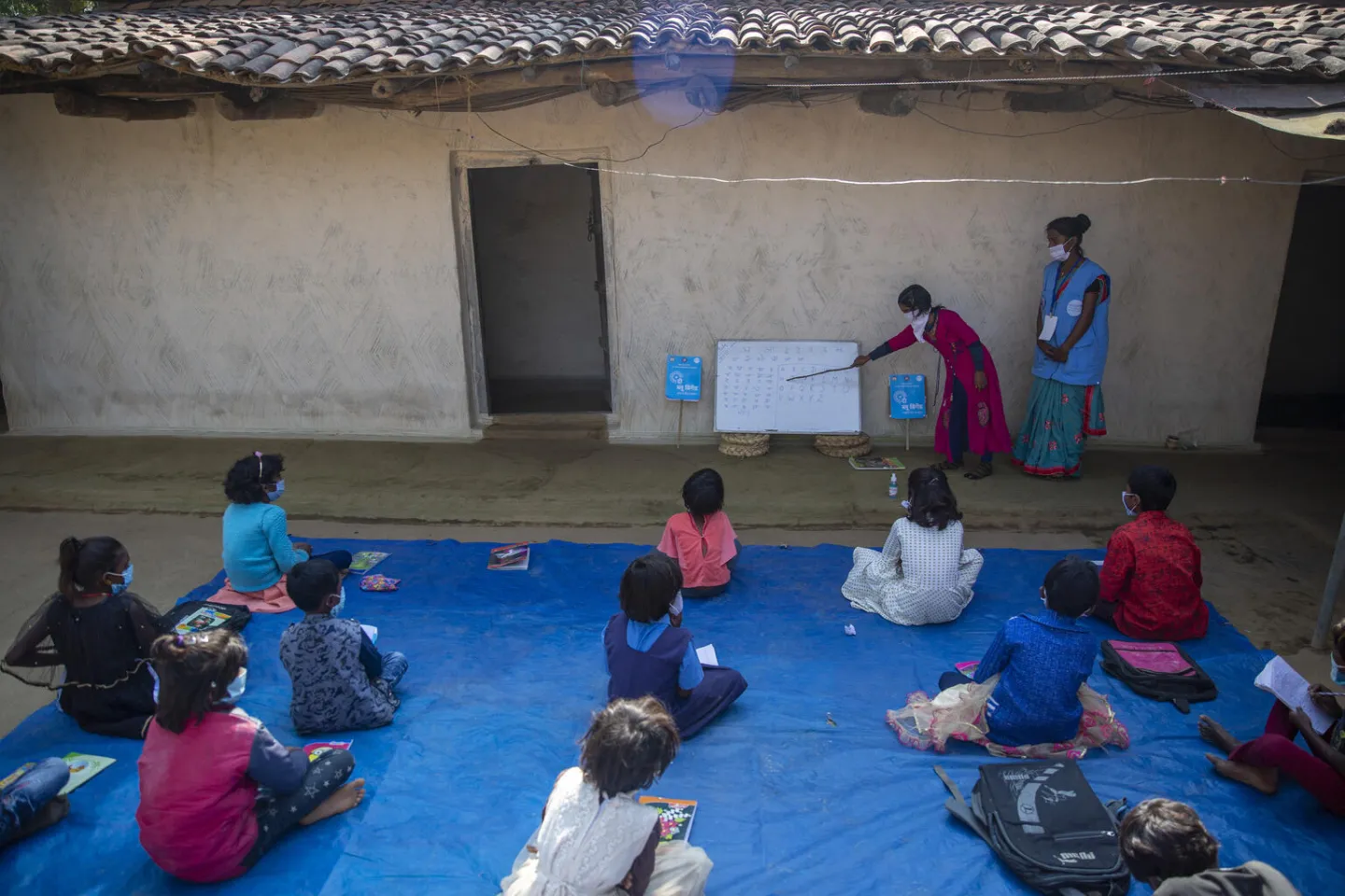 A &lsquo;Blue Brigade&rdquo; volunteer teaches children in the compound of a house under Blue Brigade initiative in village Adhina Salka, district Surajpur, Chattisgarh.