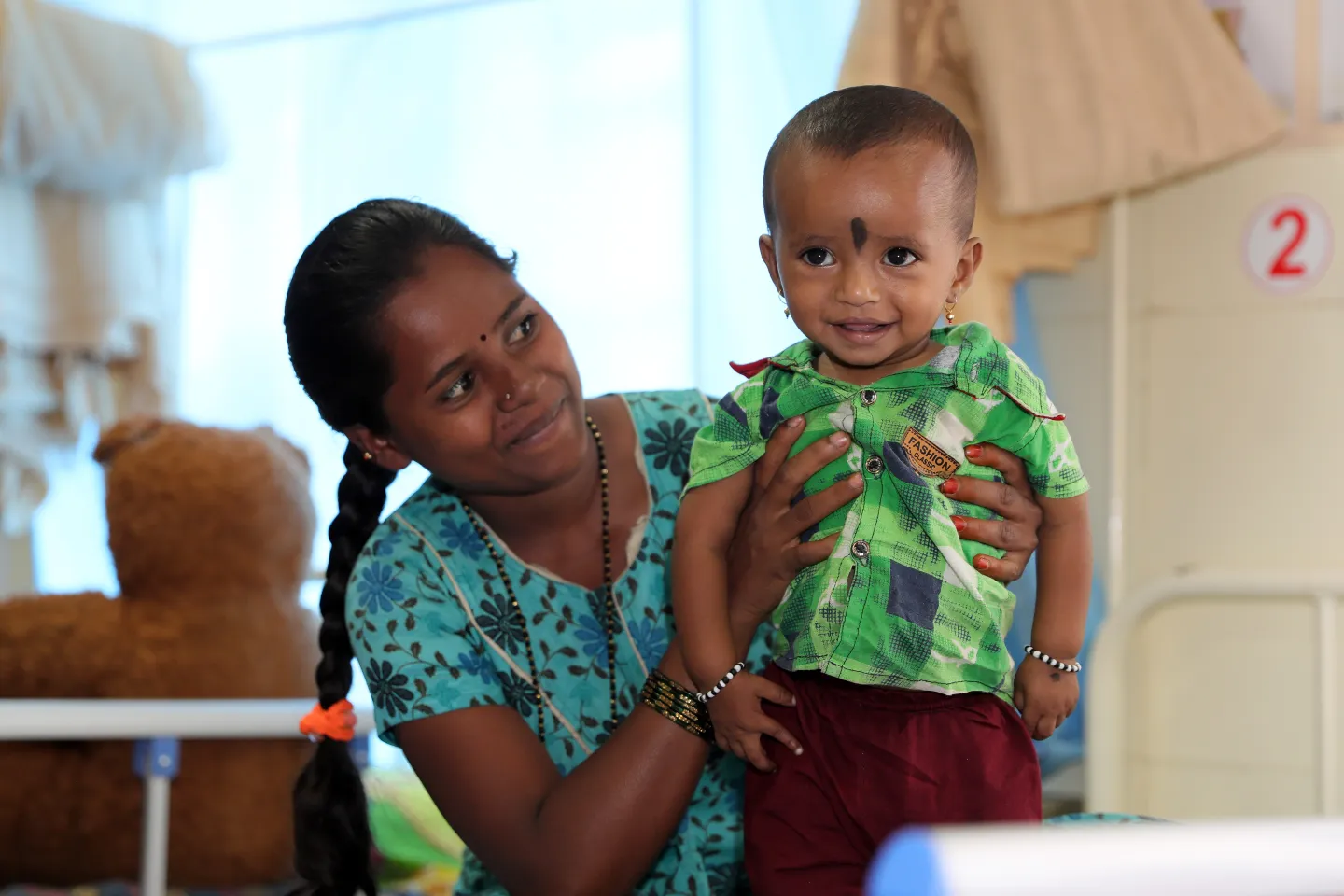 A Young happy mother looking at her son who has improved with handsome weightgain after getting treated for SAM in Chikkabalapur Nutrition Rehabilitation Centre (NRC) Karnataka.