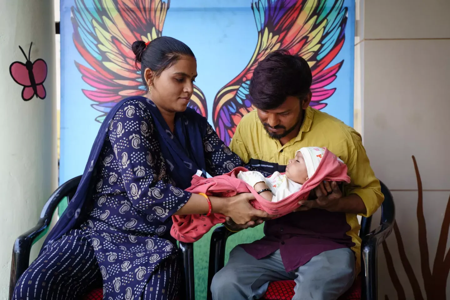 After receiving his vaccination, Tejas is gently handed over by Khushbu to his father, Sanjeev, as the family prepares to head home.