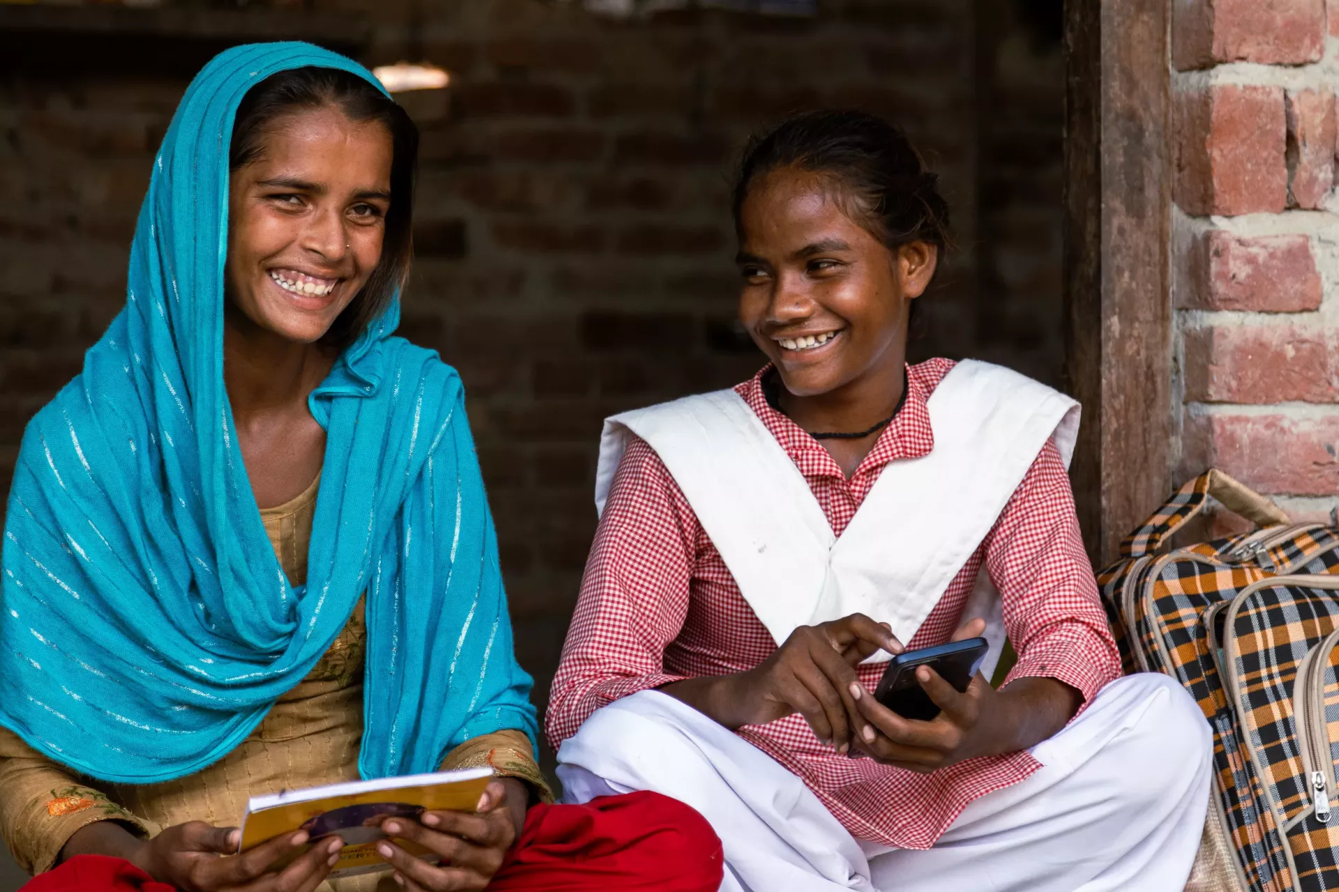 Two young women smiling and laughing lookin at the camera