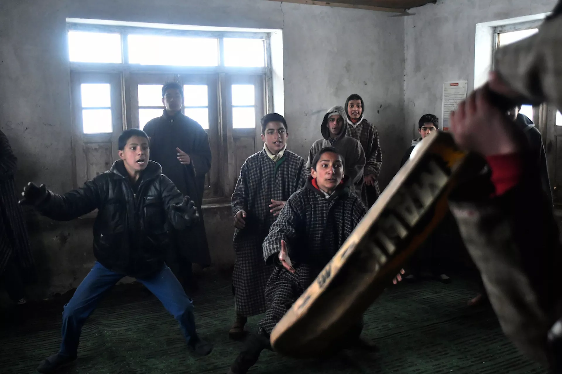Children playing cricket in classroom.