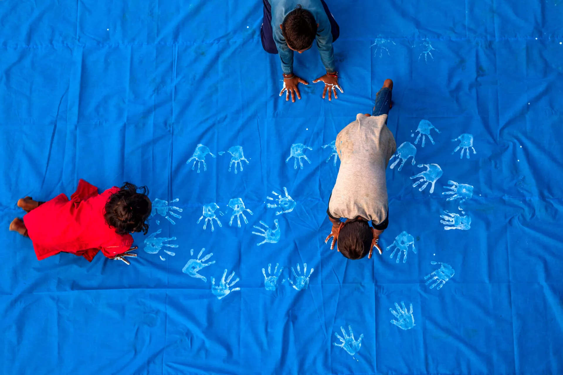 A child painting with blue paint using their hands