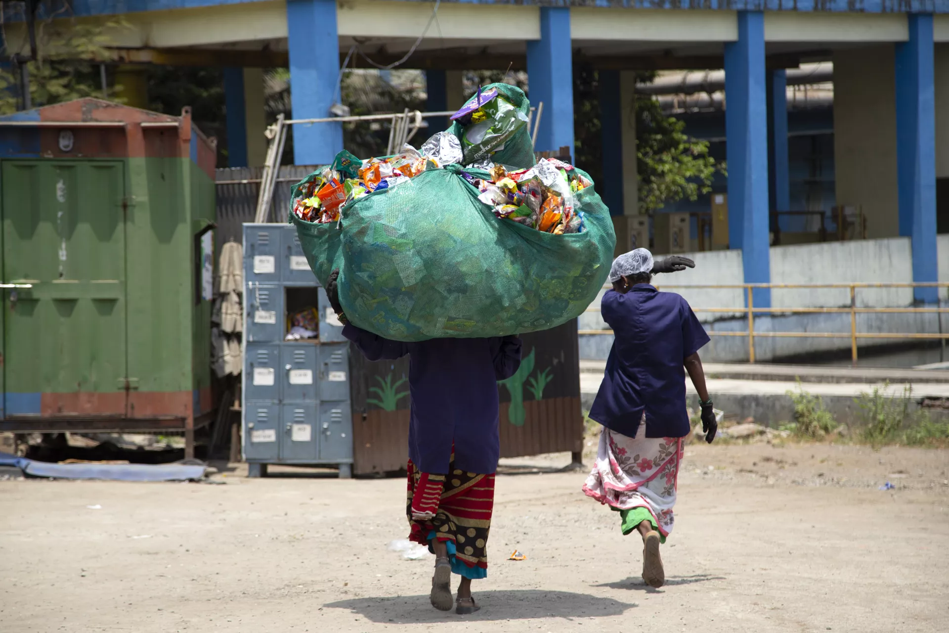 A rag picker woman carrying a heaps of segregated waste on her head at Waste management centre at Samarth Bharat Vyaspeeth (SBV), a social organisation, in Thane, Maharashtra , India on April, 18, 2022.
