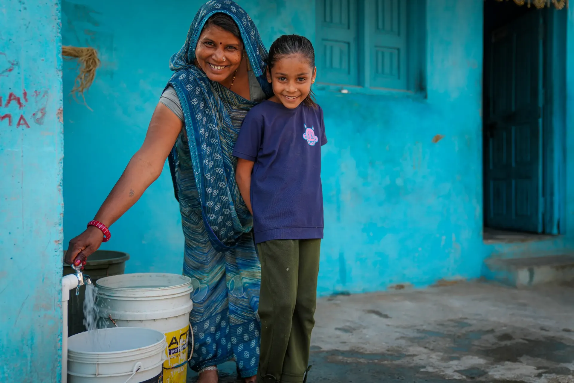 30-year-old Shanti Bai and her seven-year-old daughter Garima fill water from the tap now installed at their home in Kotdi village. 