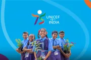 Five smiling Indian school children in blue uniforms holding potted plants, with the &amp;quot;UNICEF with India 75&amp;quot; logo on a bright blue background.