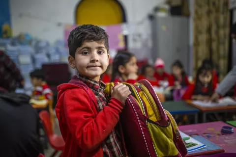 A boy holds his school bag as he sit in a classroom in Ranbir Pahal Kindergarten, Jammu. The Early Childhood Care and Education programme of the government aims at the pre-school children in the age group of 3-6 years. 