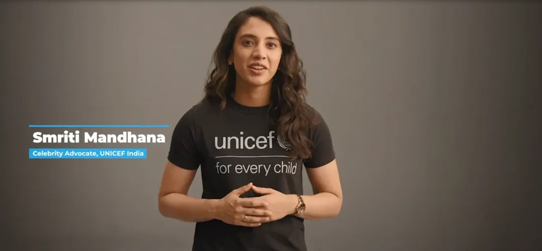 Person in black UNICEF &ldquo;for every child&rdquo; T-shirt addresses camera against plain background.