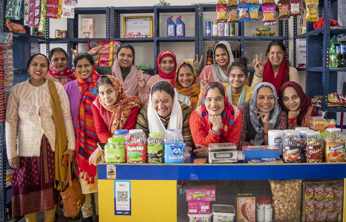 A group of women smiling and laughing in a kirana store