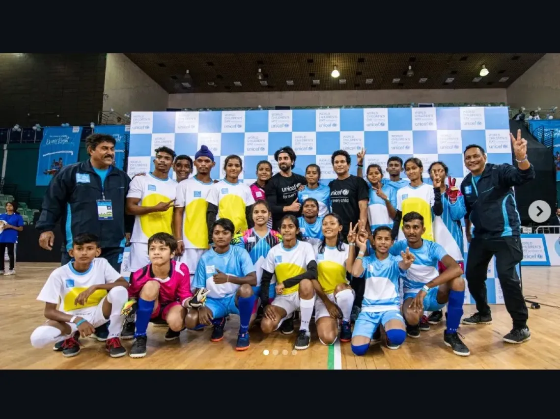 UNICEF India National Ambassador Ayushmann Khurrana and cricket legend Sachin Tendulkar pose with a group of young football players in blue and white jerseys at a UNICEF World Children's Day event.
