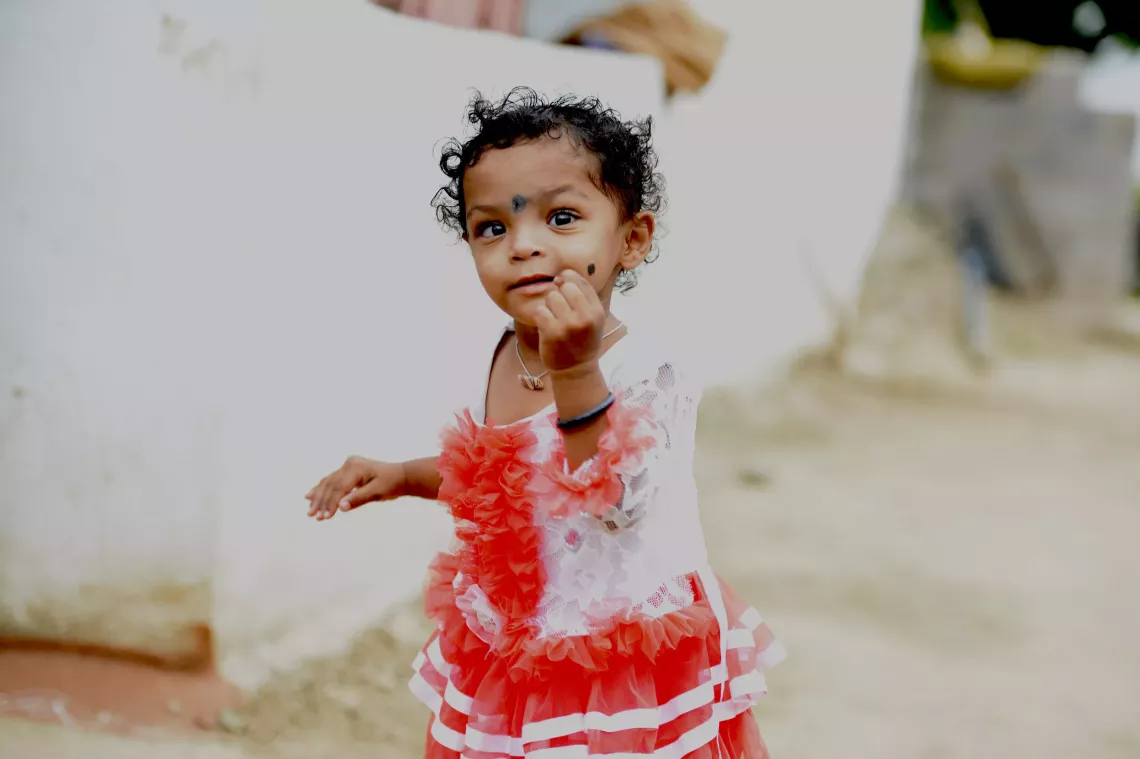 A girl child plays with a blue background behind her