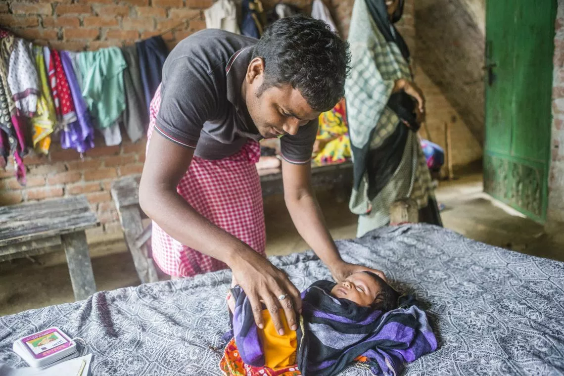 Vijay Gaud comforts his one-month-old daughter, Kushboo, during a visit from Dr Yasmin Ali Haque, UNICEF India Representative (not in the picture), as they observe home-based newborn care in Chaubeypur.