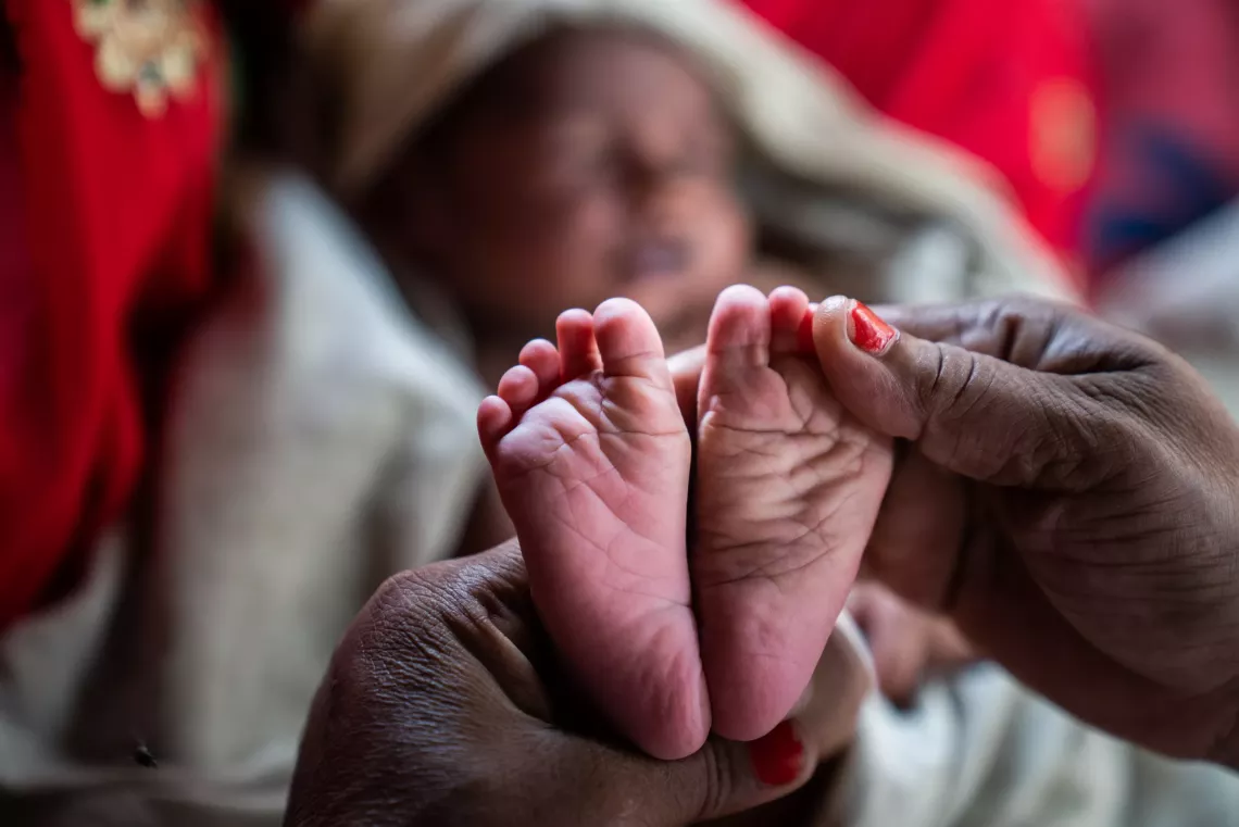 Kiran Devi, an Accredited Social Health Activist (ASHA) examines the newborn child as part of Home Based New Born Care inside a hamlet in Shrawasti, Uttar Pradesh.