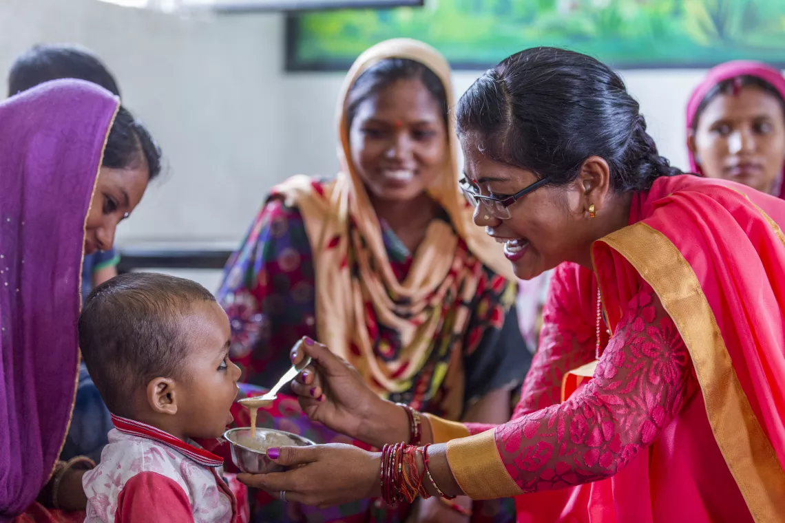 Rimpi Rani, an Aanganwadi worker feeds a child during a meeting as part of Village Health and Nutrition Day (VHND) in Motipur Kala Aanganwadi Centre in Shrawasti, Uttar Pradesh.