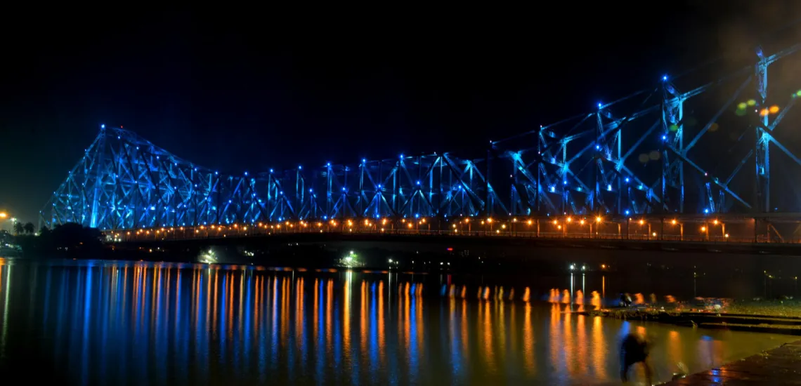 A bridge spanning across water has blue lights along it
