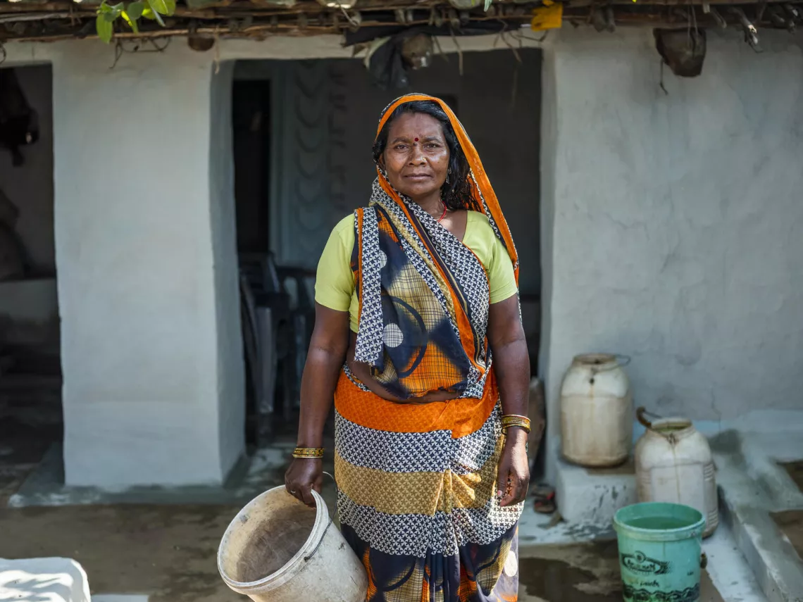 Keshkali holds a water bucket at her house in Jamunhai, Chitrakoot. 