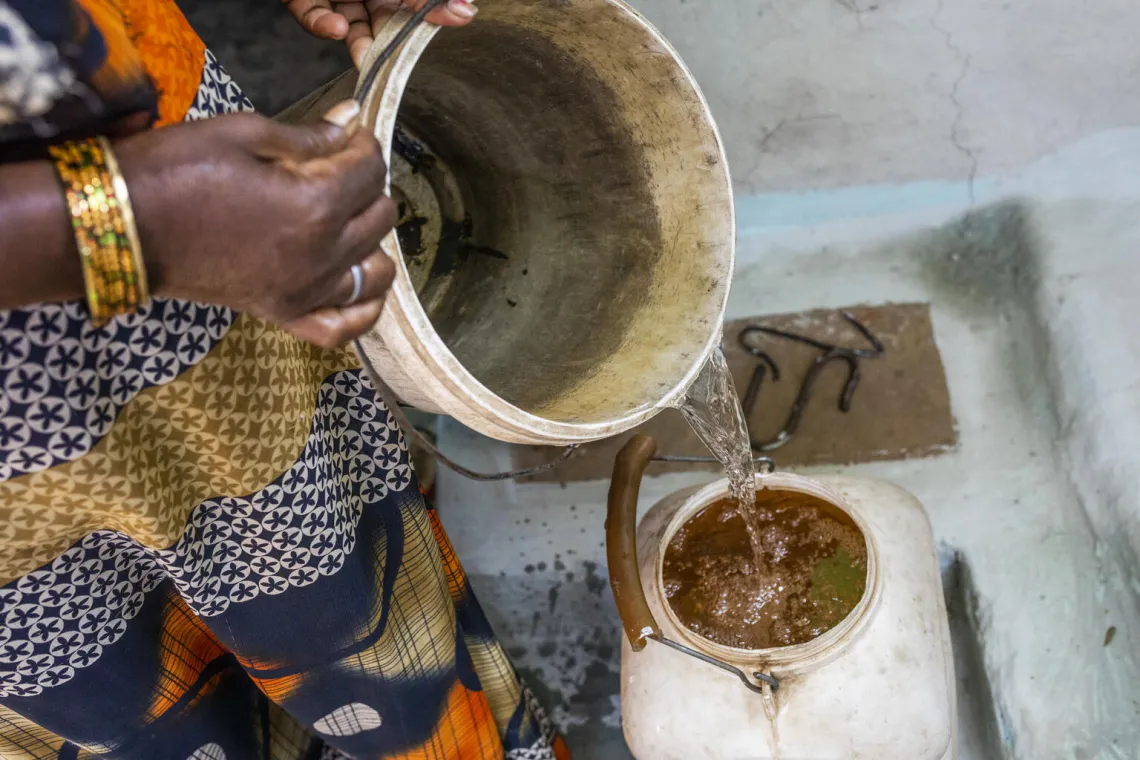 40 year old Keshkali fills water in utensils collected from closed sanitary well created by UNICEF at her house in Jamunhai, Chitrakoot.