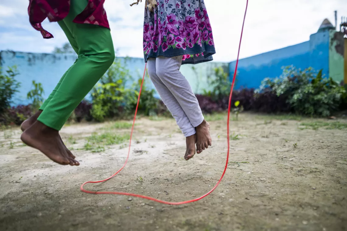 Two girls in a playground skipping with a role