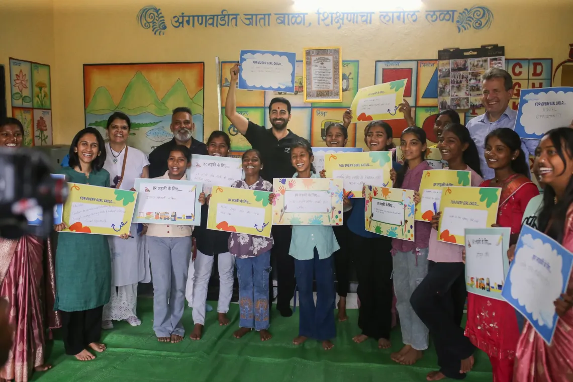 Ayushmann Khurrana, UNICEF India National Ambassador, raises his 'For Every Girl Child' placard alongside adolescent girls holding their own placards inside a decorated Anganwadi centre in Maharashtra.