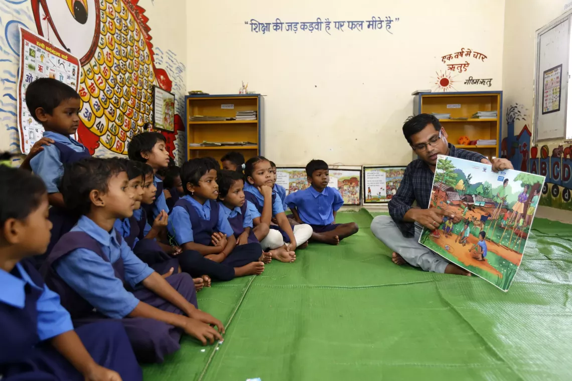 Teacher Doman Lal Sahu engages Grade 2 students in a story discussion using a Halbi-language poster at a primary school in Pendalnar, Sukma, Chhattisgarh.