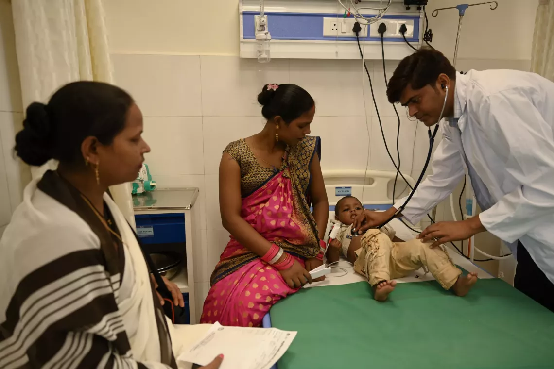 In a critical moment, Dr. Gyan Prakash Gupta, a Medical Officer at the Pediatric Intensive Care Unit, examines the fever symptoms of two-year-old Arpit Vishwakarma at the Community Health Center