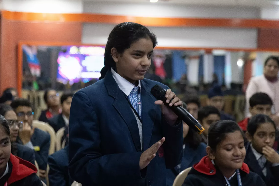a young girl with a microphone in her hand asking a question 