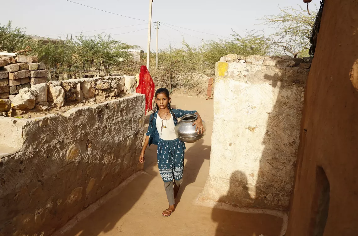 10-year-old Nirma is carrying a pot of portable water from the storage tank inside their house in Kanasar village, located in the drought-prone region of Phalodi district, Rajasthan, India.