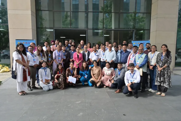 Group photograph from a two-day media workshop on childhood non-communicable diseases at AIIMS Nagpur, featuring around 45 participants, including journalists and health experts. Most are wearing blue lanyards with badges, some holding certificates, with branded standees on display.