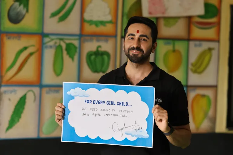 Ayushmann Khurrana, UNICEF India National Ambassador, holds a placard reading 'For every girl child&hellip; We need security, freedom and equal opportunities,' signed and dated 19/06/24, in front of a vegetable chart wall.