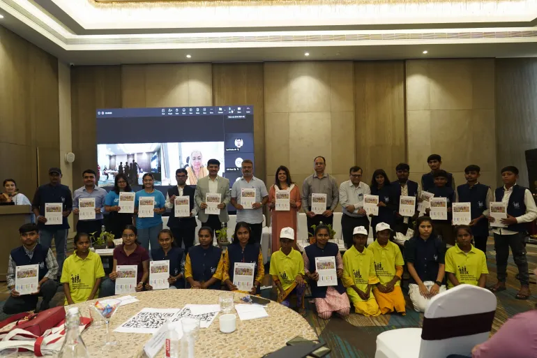 Government officials, UNICEF representatives, and adolescent participants hold up a newly launched report on adolescent mental health at a high-level conference, with a virtual speaker visible on a large screen behind them.