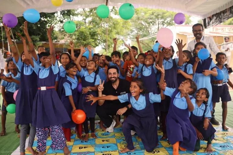 Ayushmann Khurrana, UNICEF India National Ambassador, poses with joyful schoolchildren tossing colourful balloons at an after-school engagement in Chendai Tepli village, Jalna, Maharashtra.