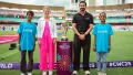 Ayushmann Khurrana is joined by Cynthia McCaffrey and a boy and girl while they stand beside the ICC Women's Cricket World Cup Trophy in a stadium