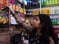  Netra, 14, takes a beverage off the shelf in her parents&rsquo; sweets and beverages shop in New Delhi, India.