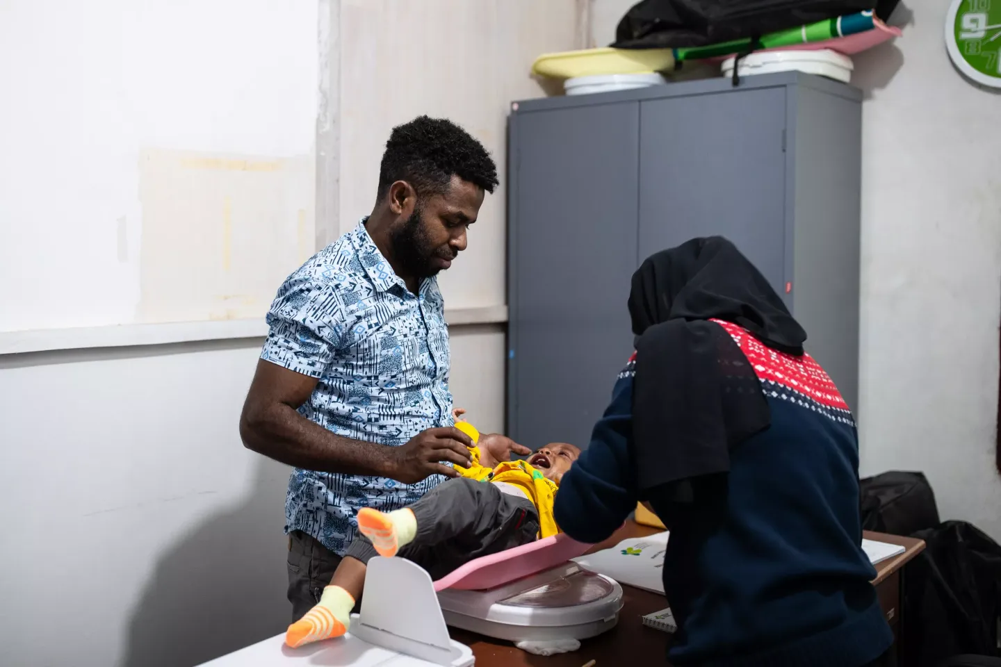 A father brings his baby to a health facility