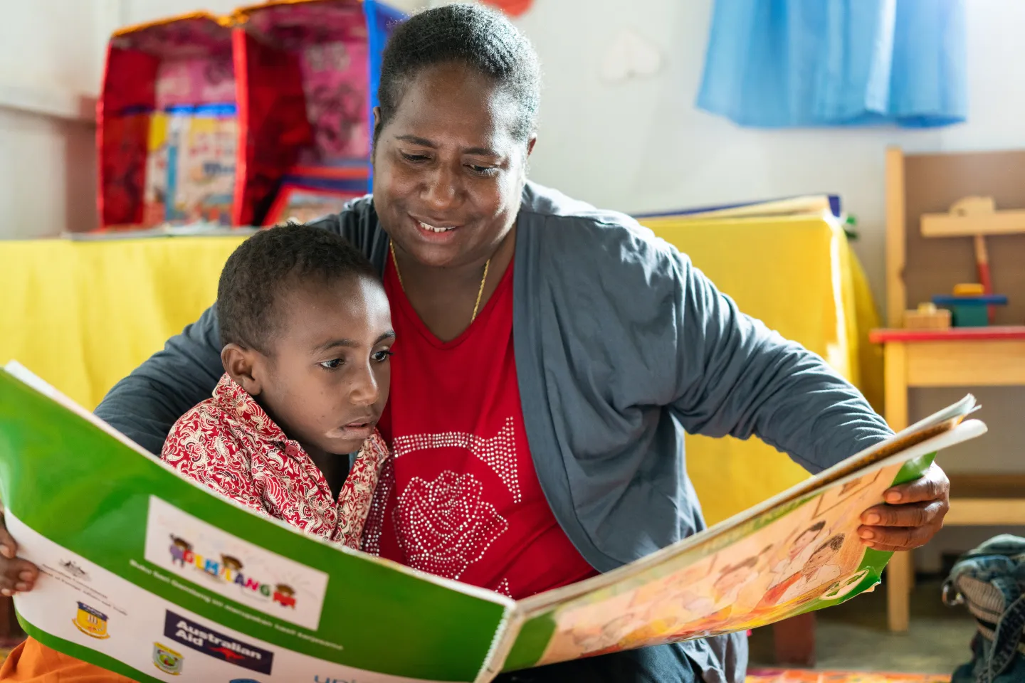 A mother reads to her daughter in a preschool.
