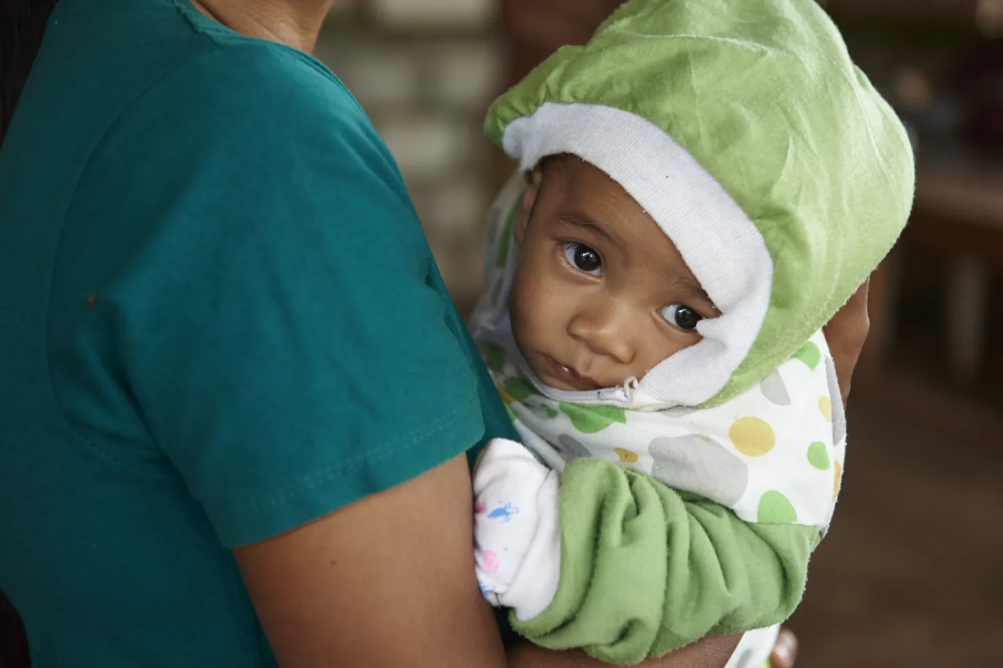A woman holds her child at the posyandu in Kupang