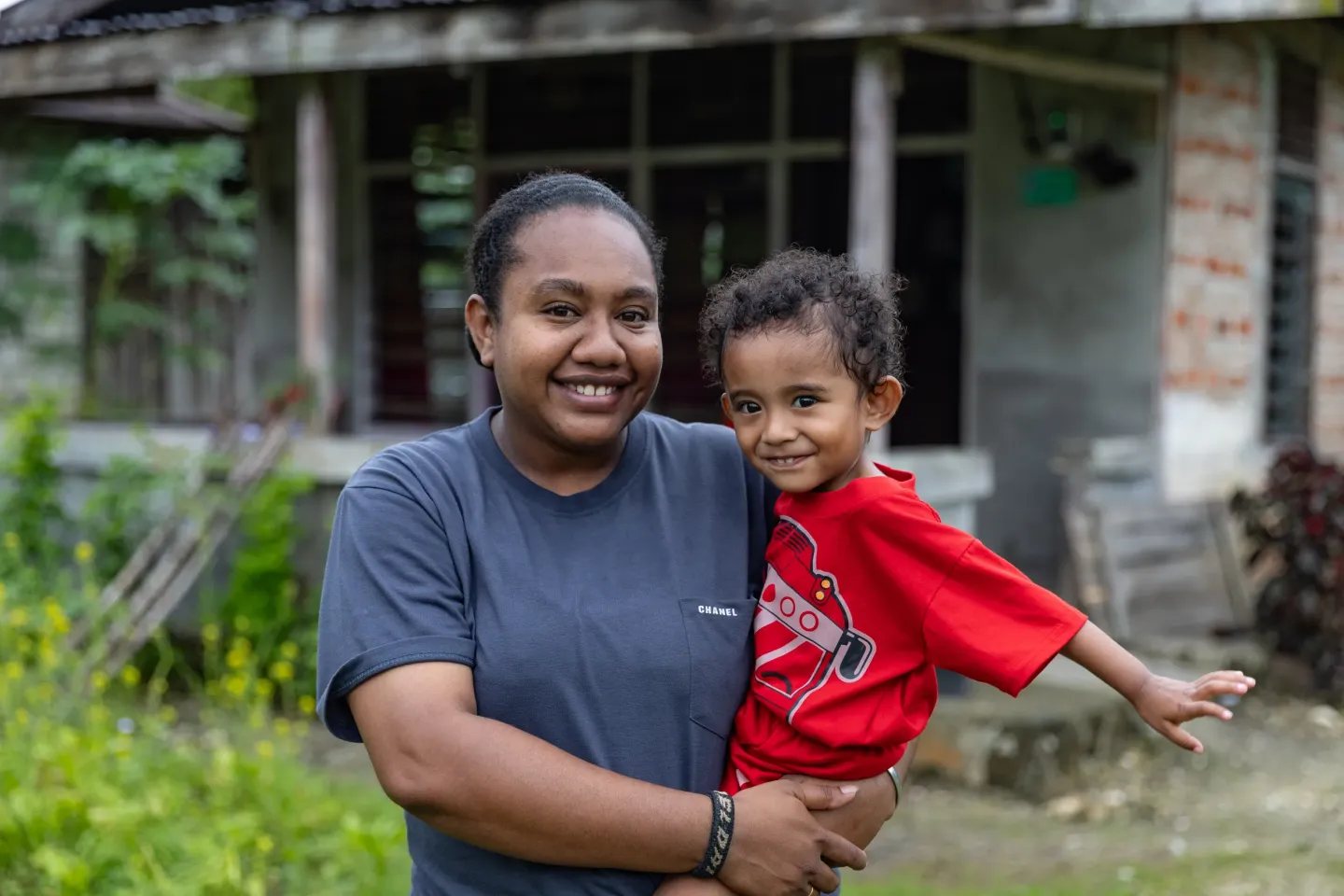 Zio and his mother smiles in front of their house