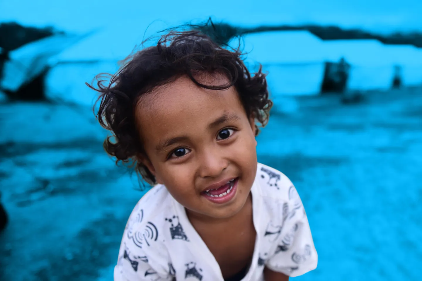 Naufal smiles in front of temporary housing for evacuees