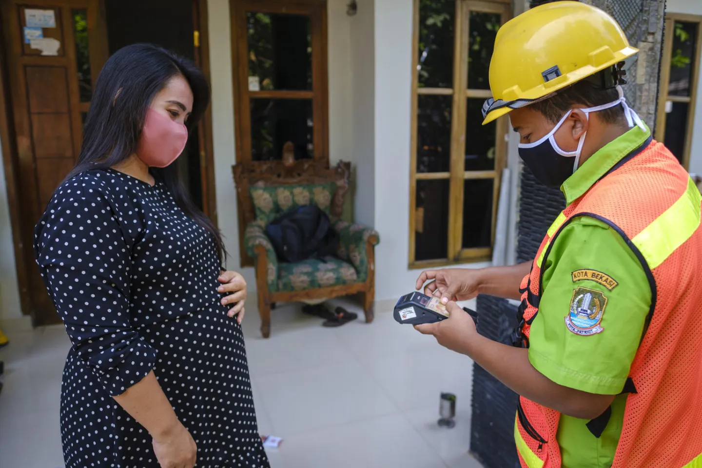 Suhrndi with the Bekasi Sanitation Department, processes a payment from local resident 