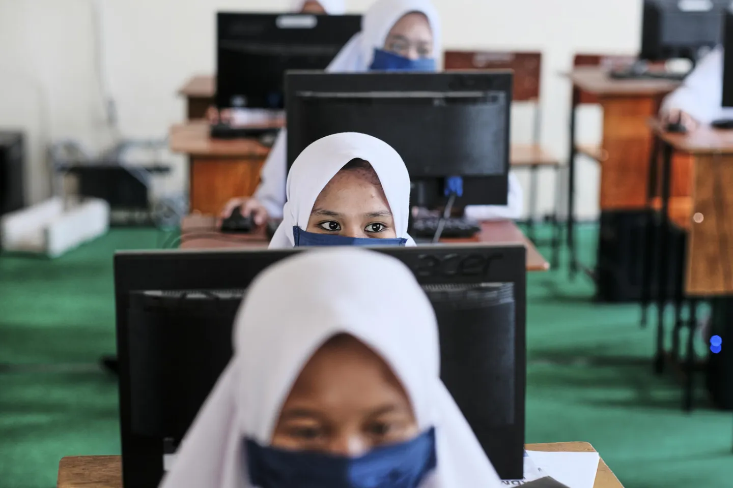 Female students sitting in a class wearing face mask and maintaining safe distance