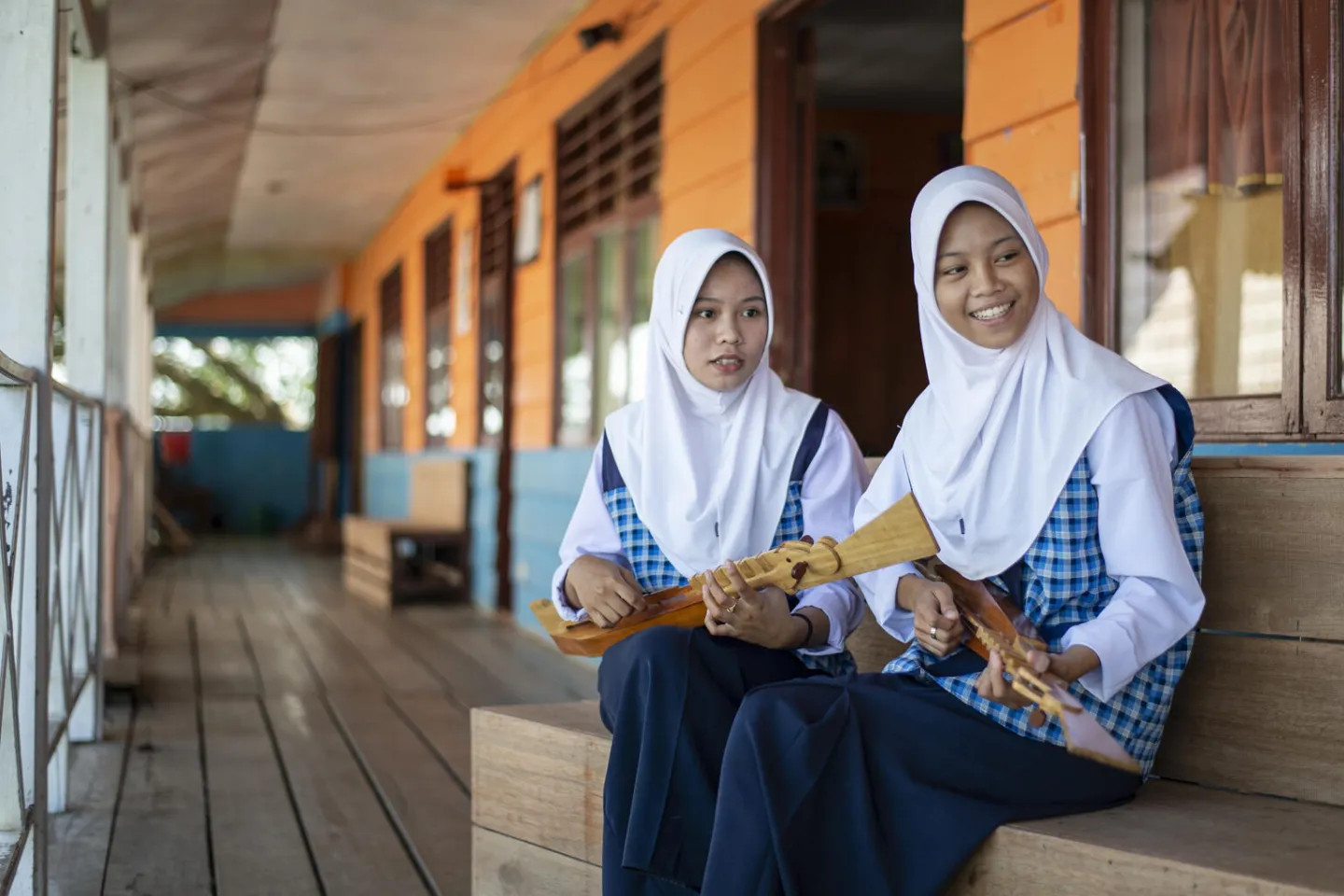 Two students sit in front of their classroom.