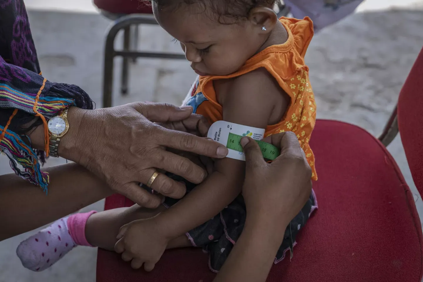 A mother measures the mid-upper arm circumference of her child 