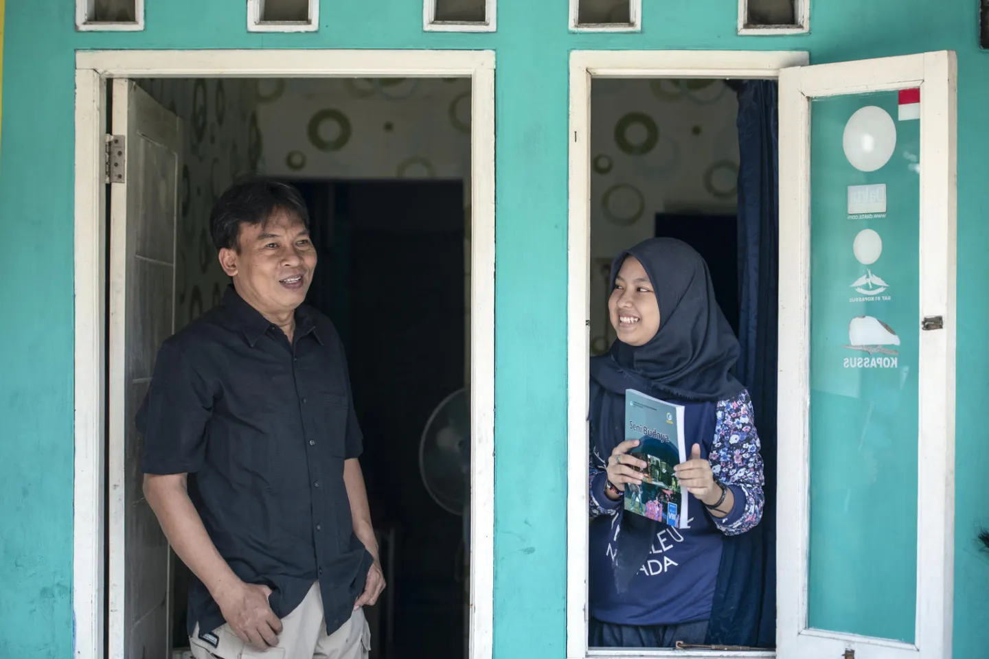 A father and a daughter standing in front of their house 