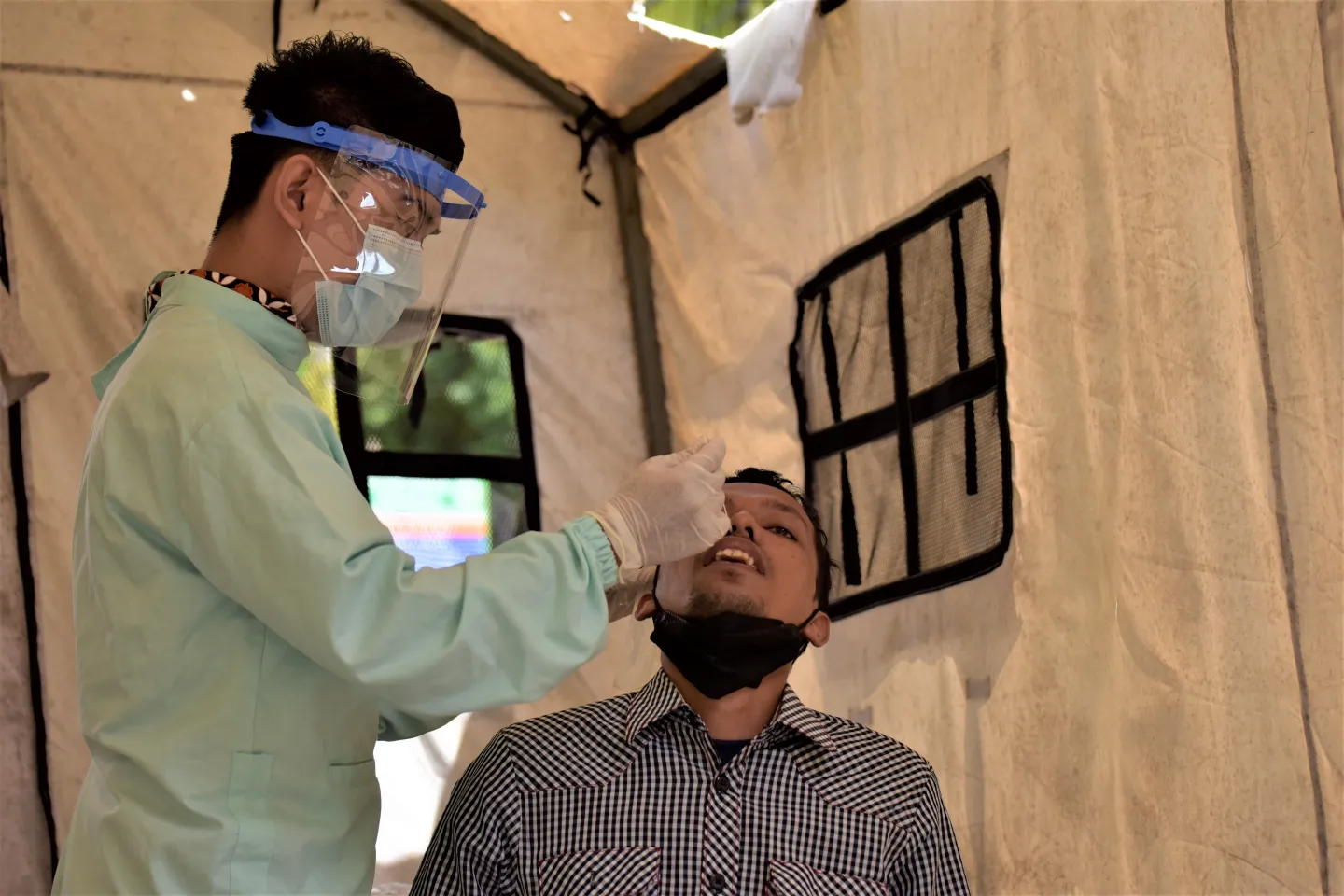 Lab analyst Panca Rakhmat takes a sample from a patient using an antigen test kit that detects the virus that causes COVID-19 at Puskesmas Binanga in Mamuju, West Sulawesi Province.