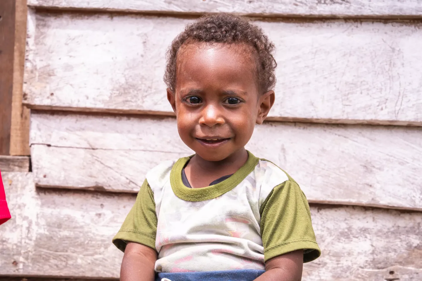 Nino, 2, smiles to the camera in front of his house in Hingk District, Arfak Mountains, West Papua, on 18 March 2025