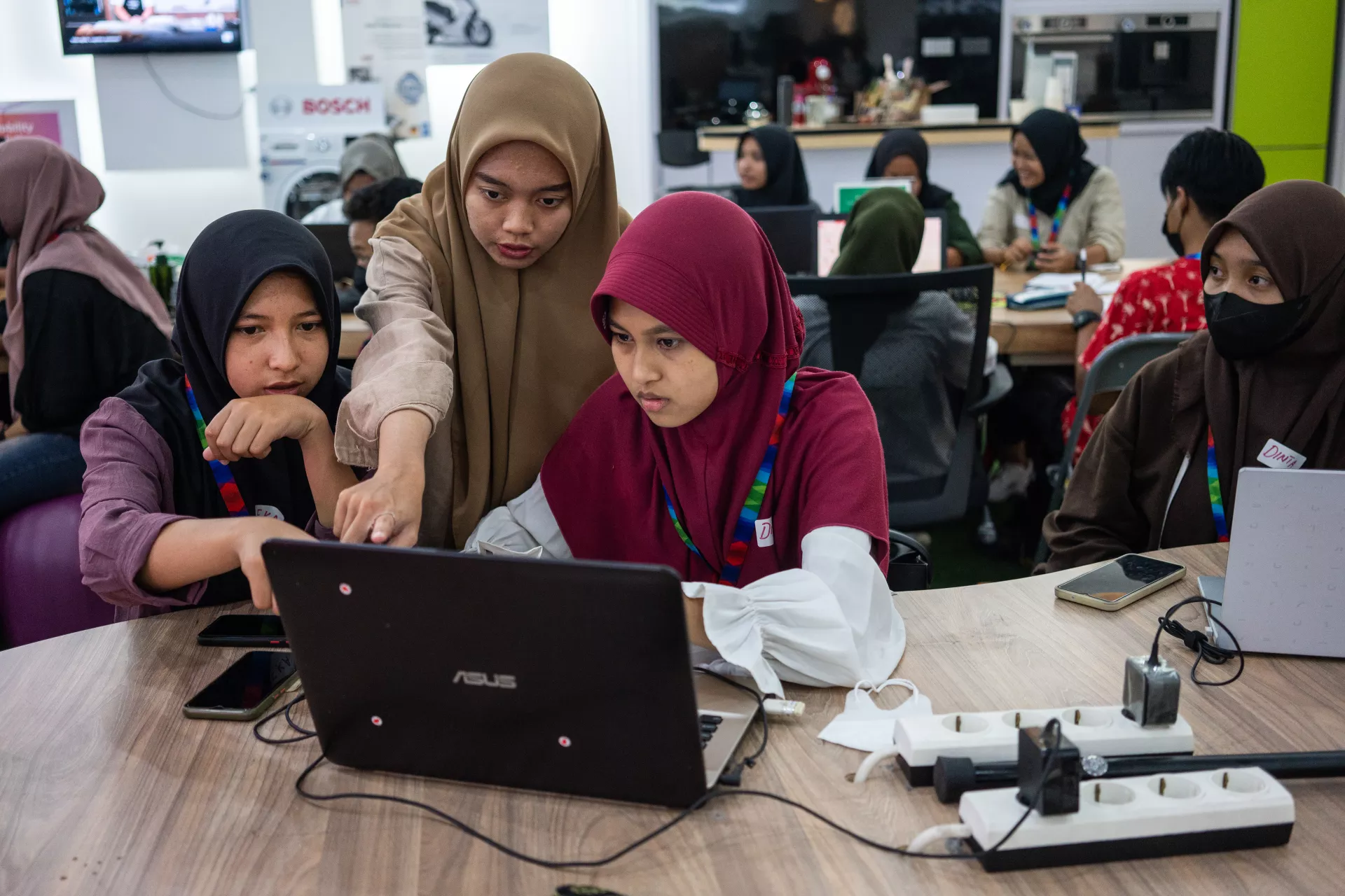 Three girls looking at a laptop and discussing during a training
