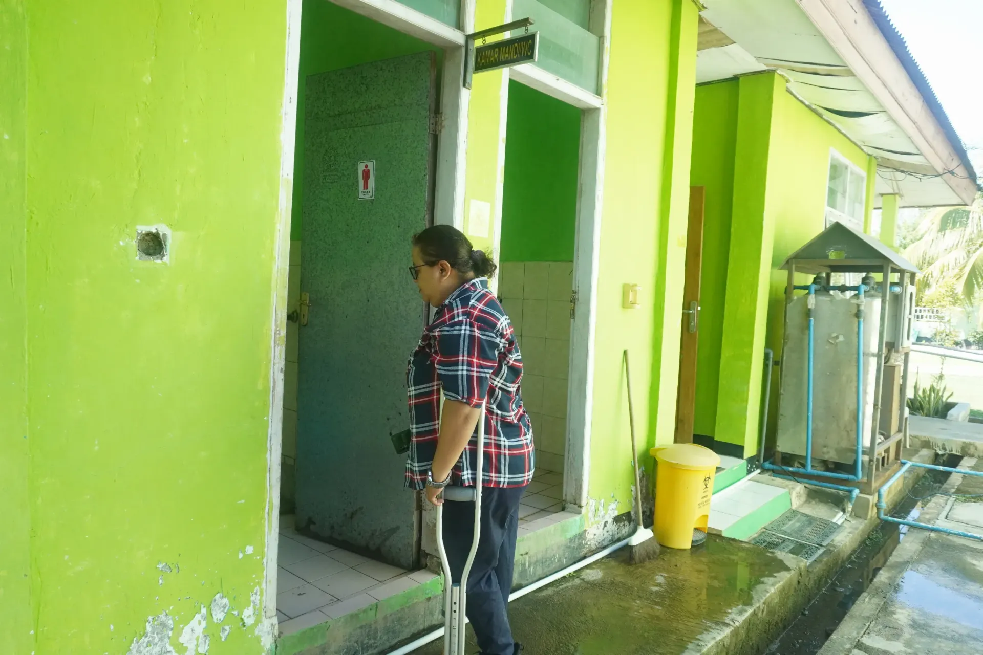 Yomi observes sanitation facilities at Puskesmas Poto, Kupang District, East Nusa Tenggara, on 2 June 2025 during the Joint Assessment of WASHFIT for GEDSI and Climate Resilience, alongside the PERIKSA Assessment across 26 community health centres in Kupang District. The initiative is supported by UNICEF and the Republic of Korea.